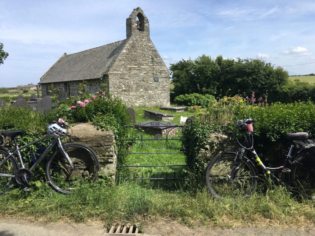 Two bikes rest at gate of Pabo Sant Church, during Off the Beaten Track, Sacred Spaces on Ynys Môn, Anglesey Guided Bike Tour.