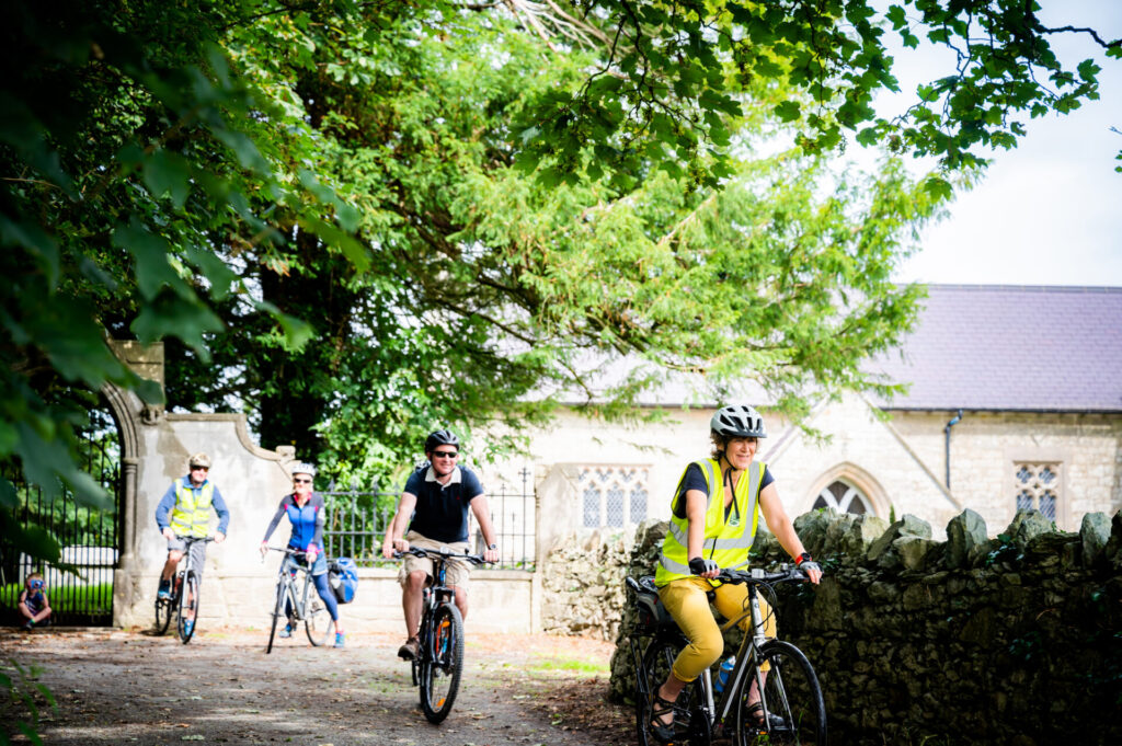 A group of cyclists cycle with a church in the background
